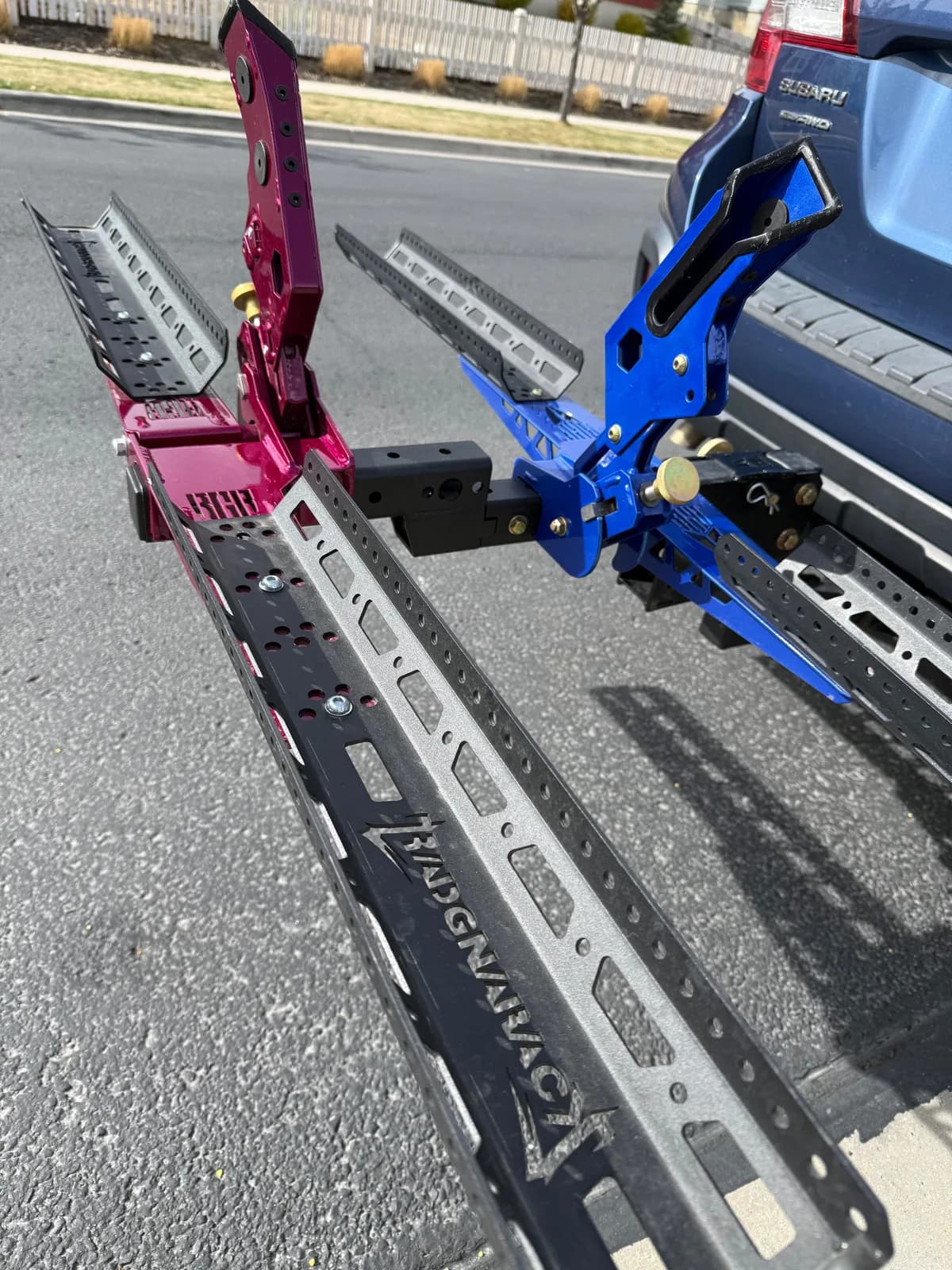 Custom magenta and blue RadGnaRack wheel trays hitch-mounted on a blue Subaru